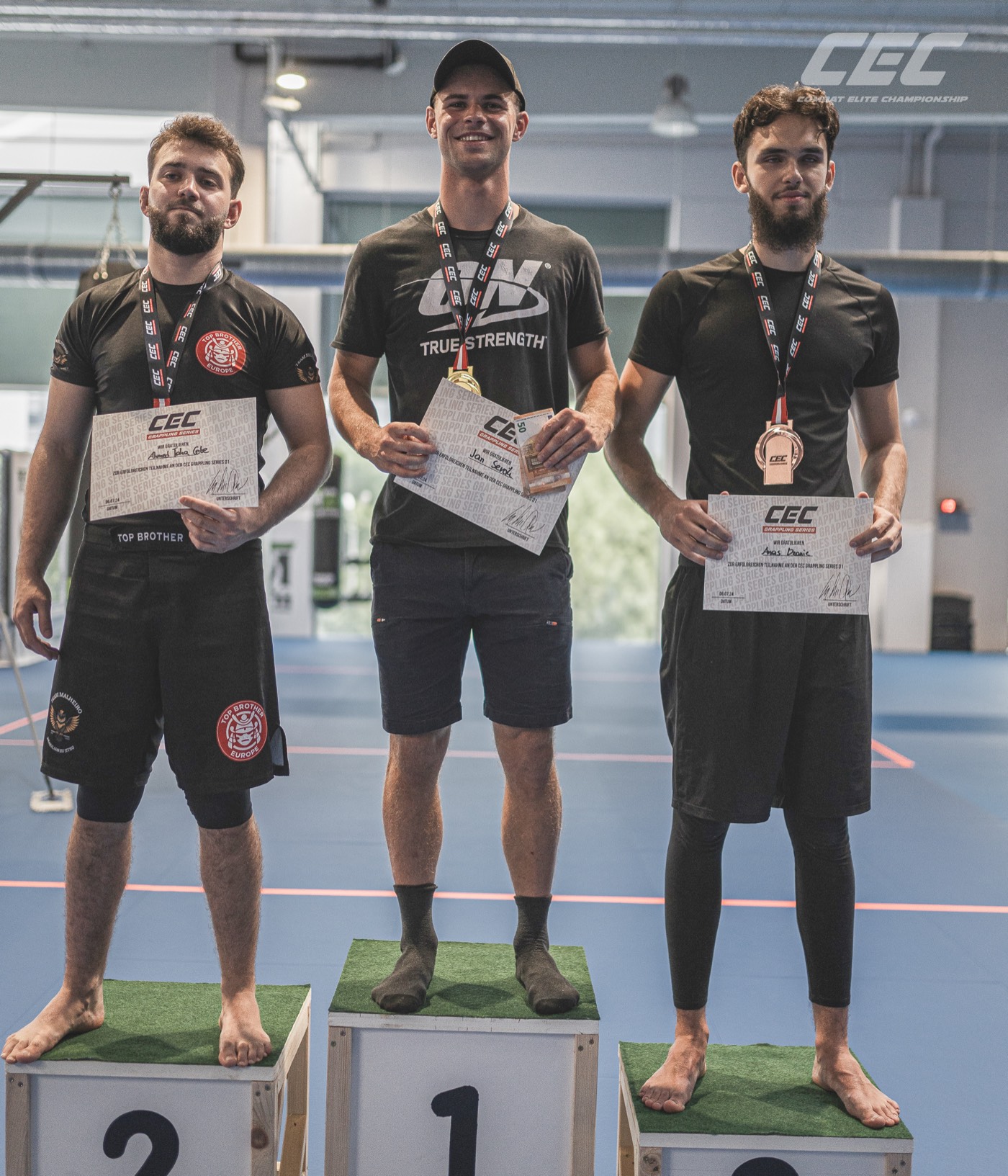 Adults podium at Grappling Series 1 — three placed athletes with CEC certificates and medals