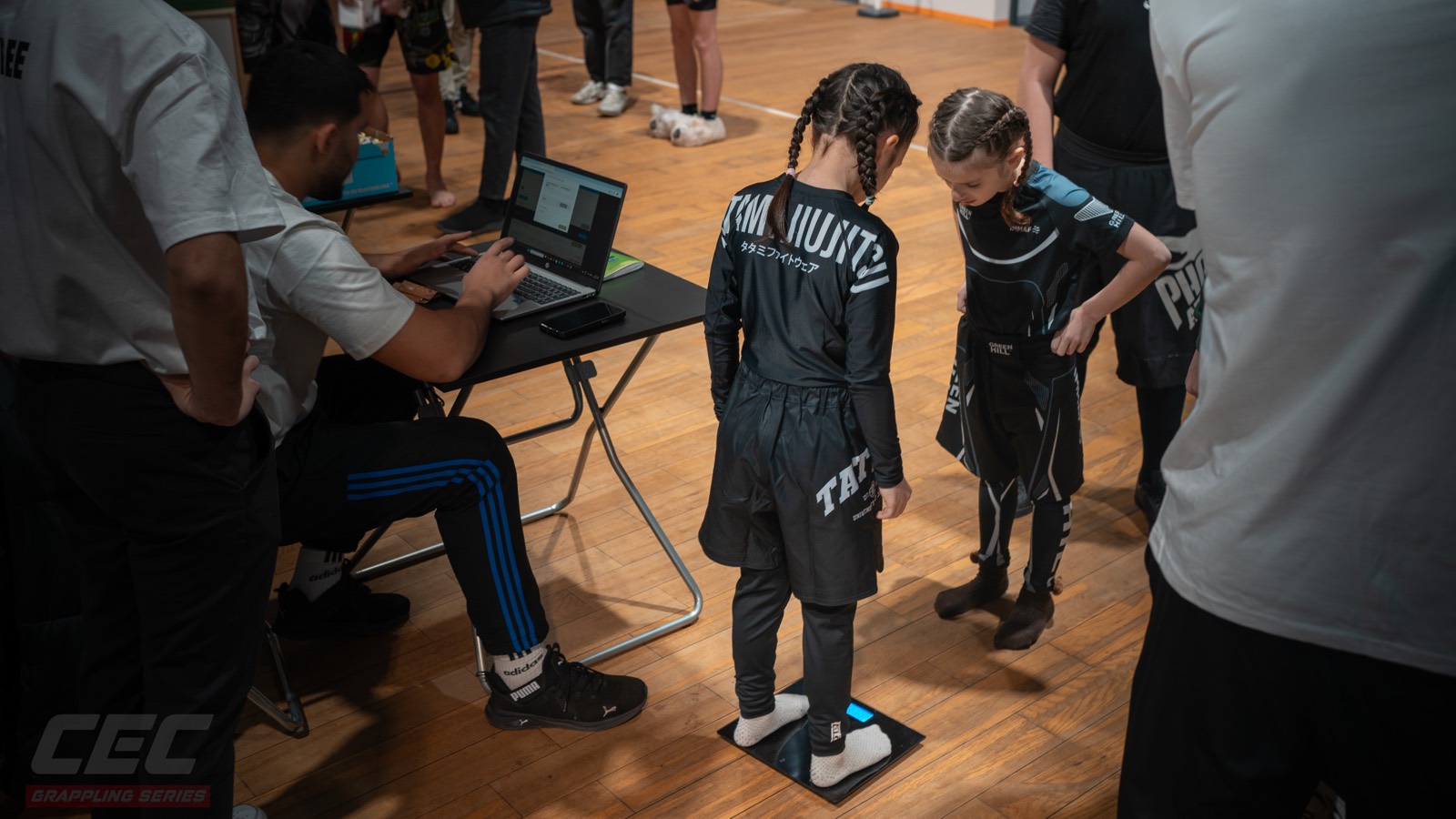 Weigh-in at Grappling Series 2 — a youth competitor on the scale, the result going straight into the laptop at the desk