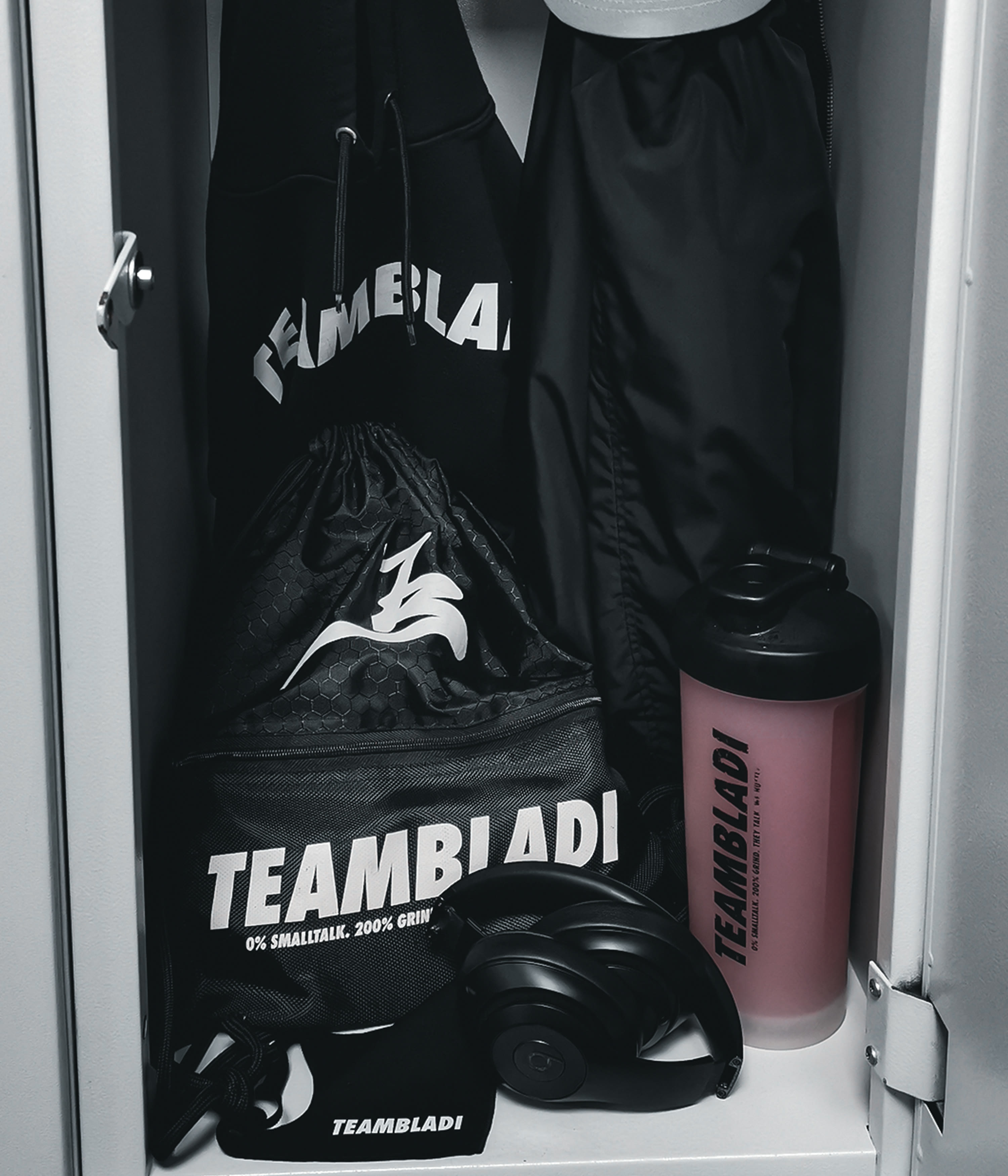 TEAMBLADI gear flat-lay — hoodie, bag, water bottle and headphones in a gym locker
